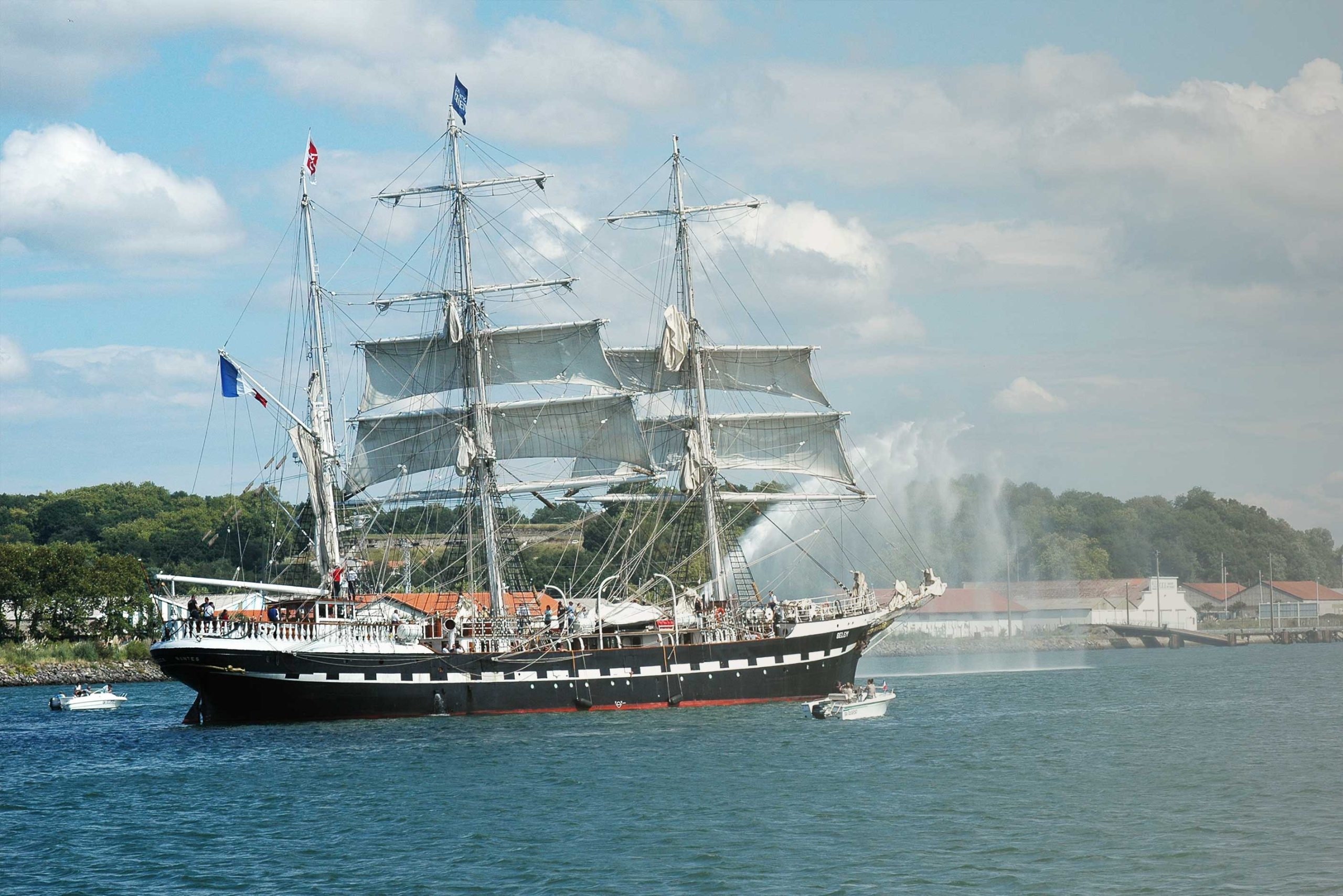 Le Belem, dans sa pleine largeur, au large des côtes de Bayonne. Des bâteaux de plaisance l'entourent.