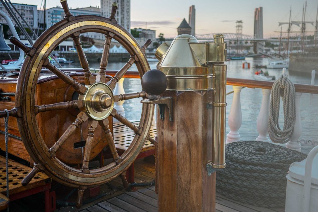 Gouvernail en bois du Belem sur le pont. Un port est visible en fond.