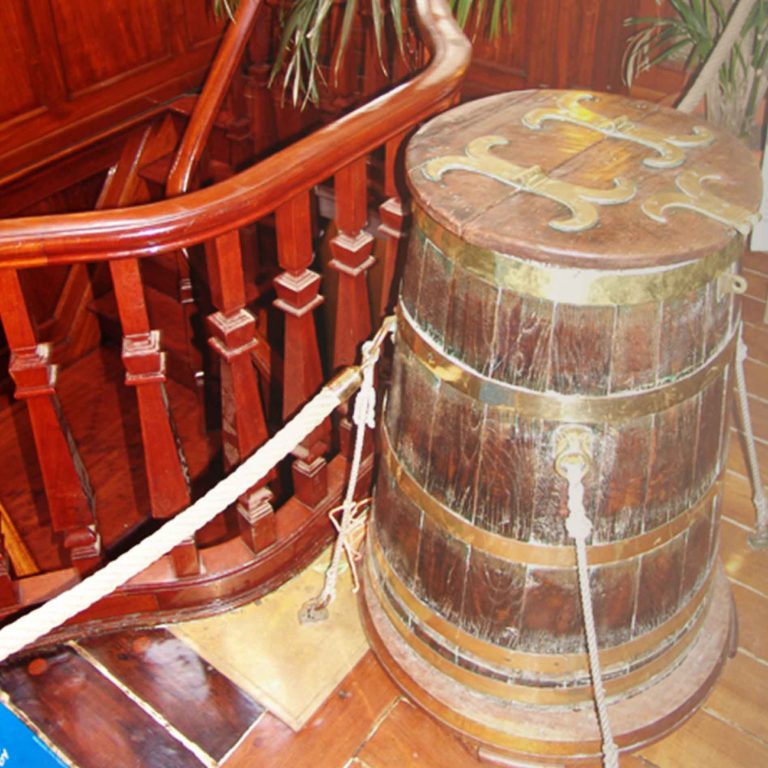 Tonneau situé à l'intérieur du Belem. L'intérieur est en bois et un escalier descendant est derrière le tonneau.